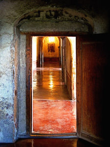 Rounding the corner of the hallway, the visitor is greeted with the distant image of a mural at the end of the long hallway, lit by a single uncovered bulb. As one approaches, the Virgin of Guadalupe appears in the mural, obfuscated by the intervening centuries. Patron Saint of the Americas, she is present in the 16th century Ex-Convento de San Pablo Apostol in Yuriria, Michoacan. This original photograph forms part of the Olden Mexico collection. © Darian Day and Michael Fitzpatrick, 2010