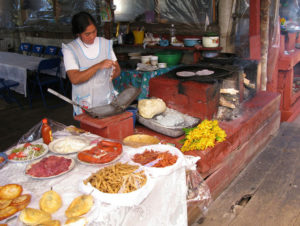 This vendor is one of many lining the main dock on Lake Zarahuen. Her offerings of chiles rellenos, prickly pear cactus salad, carne asada, chorizo and fish include handmade tortillas. The bunch of yellow squash blossoms make a delicious filling for quesadillas. © Linda Breen Pierce, 2009
