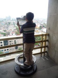 A young visitor to the Revolution Monument enjoys panoramic views of Mexico City from one of the coin-operated binoculars positioned around the observation deck © Anthony Wright, 2012