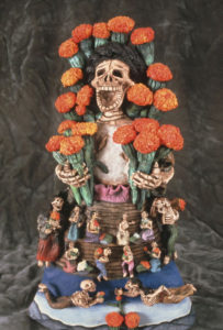 Laughing in the face of death, a skeleton bedecked in marigolds holds two bright bouquets.The flowers are said to light the way home for spirits who visit the living on the Day of the Dead. Demetrio Garcia Aguilar creates this image. © Arden Aibel Rothstein and Anya Leah Rothstein, 2007