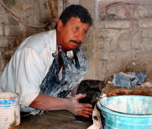 In this area of Jalisco, the typical country-workshop approach to shaping obsidian is dangerous. Here, a piece of the black glass is being pushed into a table saw. © John Pint, 2009