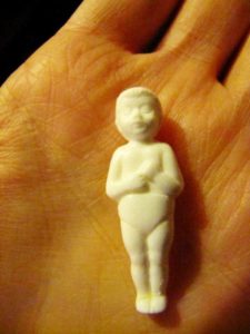 In Mexico, dolls like this tiny image of Baby Jesus are baked inside the Rosca de Reyes, served on Epiphany. Whoever gets the image in his or her serving of bread becomes the doll's godparent and must host a party for all those sharing the rosca on the Dia de la Candelaria, or Candlemas. © Tara Lowry, 2014
