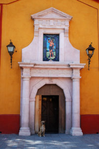 A dog sits in the shade beside a doorway to San Sebastián Mártir Church in Bernal, Querétaro. Bernal has been designated a "Magical Town." © Jane Ammeson 2009