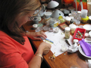 Martha Leticia López Luna places a tiny bit of feather on her painting of the Isla de Janitzio rising over Lake Pátzcuaro.