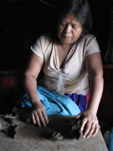 Antonia Cruz Rafael of Ocumicho, Michoacan is a skilled ceramist. Sitting in her home, she molds the parts for a fanciful clay goat. © Travis Whitehead, 2009