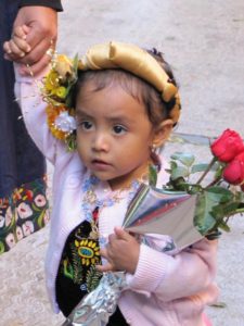 A young Oaxacan dressed up for the special day — the feast day of the Virgin of Guadalupe. The little girl carries roses, the Virgin's favorite flower. © Tara Lowry, 2014