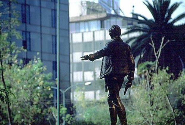 As if gesturing to pedestrians to not cross the Paseo de la Reforma until the traffic clears, a monument to one of Mexico's heroes gazes into the Zona Rosa. Photography by Bill Begalke © 2001