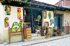 A menagerie of colorful and rustic-finish furniture spills out of a doorway, hinting at the variety inside.