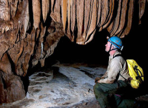 Canadian Chris Lloyd admires draperies above a floor covered with delicate calcite crystals in Cueva de la Luna Llena, which can only be reached via a 40-meter rappel. This Mexico cave is located in the state of Michoacan. © John Pint, 2010