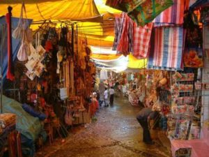 It is rather incredible that all processions to the church must run the gauntlet of this souvenier market that becomes a feeding market nearer to the church. The colorful awnings make the passage a veritable tunnel that suddenly opens upon the pilgrimage terminus.