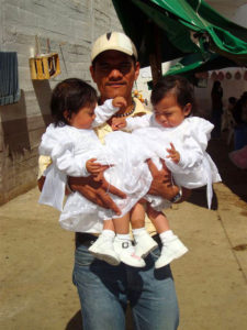 An inmate at the Oaxaca State Prison holds his two daughters. Dressed in frilly white gowns, the little girls will be christened by prison chaplain Reverend Spencer Thompson. Maintaning strong family ties helps prisoners adapt better upon their release. © John McClelland, 2010