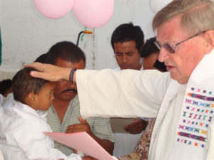 Prison chaplain Reverend Spencer Thompson officiates at the christening of a prisoner's little boy. This is a part of his pastoral care at the Oaxaca State Prison. © John McClelland, 2010