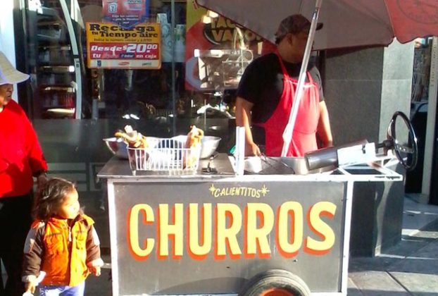 A little girl is attracted by the scent of hot, sugary churros, a deep-dried bread. The owner of this cart in Tijuana cooks this delicious treat on the spot. © Henry Biernacki, 2012