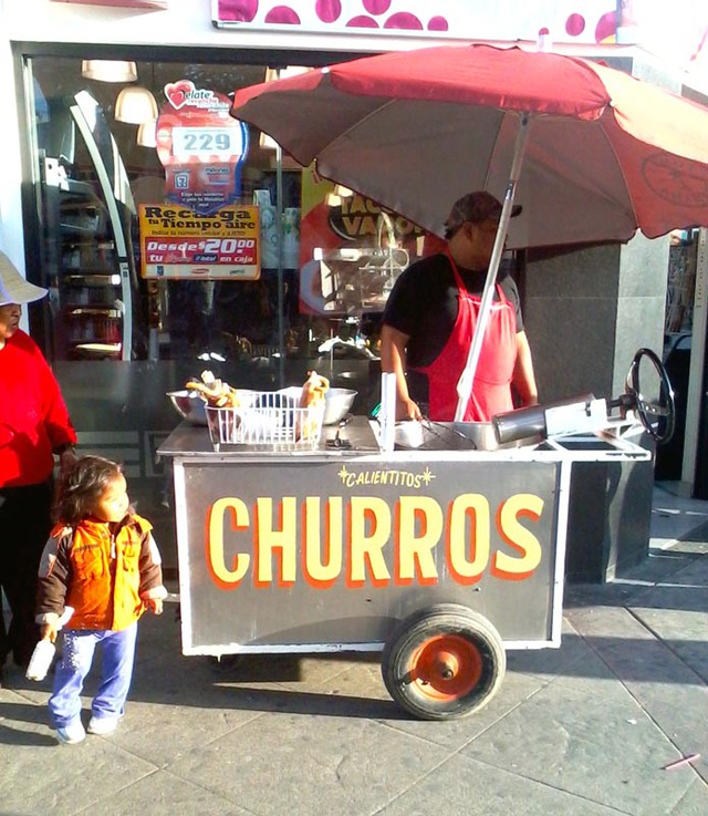 A little girl is attracted by the scent of hot, sugary churros, a deep-dried bread. The owner of this cart in Tijuana cooks this delicious treat on the spot. © Henry Biernacki, 2012