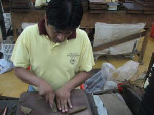 The finishing man in Mexicoi's Te-Amo cigar factory was a study in concentration. He worked with a strange, fat moon-shaped blade — known as a chaveta — as he crafted the final touches to each cigar. Oblivious of my clicking away, he cut and fit. My high-speed camera failed to catch his hands, except as a blur. © William B. Kaliher, 2010