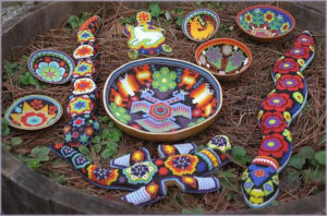 A sampling of beaded Huichol art objects, including gourd six offering bowls, two serpents, an iguana and a turtle with a white deer on its back. © Robert Otay, 1997