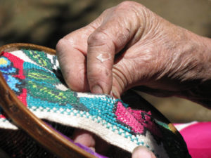 Hermilinda's dexterous hands run a needle through the guanengo (blouse) to bring the colorful blossoms to life. The Mexican artisan is a native of Cocucho, Michoacan. © Travis Whitehead, 2009