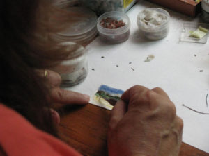 Creating a work of art with bird feathers requires long hours of tedious work. Here, Martha Leticia Lopez Luna uses tweezers to install a feather on her painting.