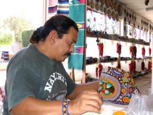 Huichol artisan and philosopher Kupihu'ute-Itzpapalotl uses a maguey thorn or a pick made of abalone to preciesely place each tiny bead on his masks and votive art. © Erin Cassin, 2006