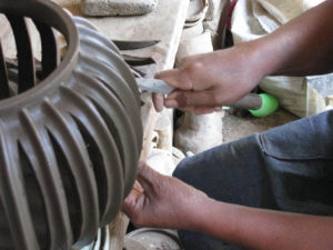 Removing slices of clay from between the ribs of a cactus-shaped pot requires delicate precision.