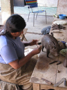 Cecilia places small adornments on a realistic clay pig.