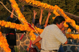 Men from the village help to raise an arch of marigolds in Cuchuchucho, Michoacán.