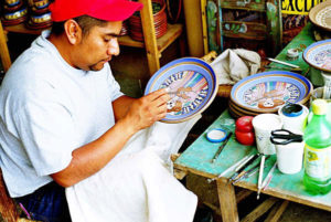 Rogelio Martínez paints Catrinas on ceramic plates.