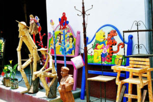 Tigger gets into a tussle with Winnie the Pooh on a headboard outside a Cuanajo store while Don Quixote gazes pensively into space. In the foreground, a portly wooden friar stands beneath an old-fashioned coat rack.