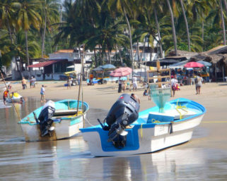 Shallow waves lap at snall boats with outboard motors on the beach at Los Ayala on the Pacific coast of Mexico. © Christina Stobbs, 2009