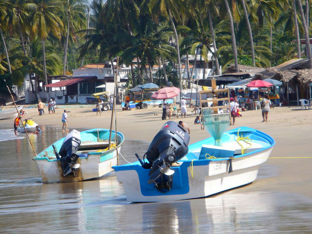 Shallow waves lap at snall boats with outboard motors on the beach at Los Ayala on the Pacific coast of Mexico. © Christina Stobbs, 2009