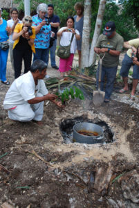 The pib, or underground oven is uncovered by the villlage shaman in Pac Chen, a tiny Maya village. The pot contains pork that has roasted overnight. The food is a part of the Day of the Dead celebration in this Mexico town. © Jane Ammeson, 2009