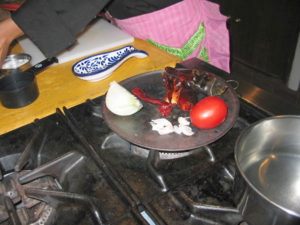 Dried chiles, onion, tomatoes and garlic in its husk are toasted on the comal to be used in the mole at the Oaxaca cooking school. © Alvin Starkman 2008
