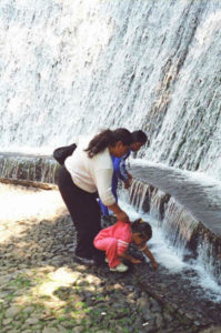 A woman and children stop to gaze in wonder at the water crashing down a wall. Numerous water formations attract visitors along the trail.
