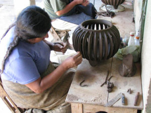 Cecilia painstakingly places tiny clay beads along the rib of a cactus-shaped pot.