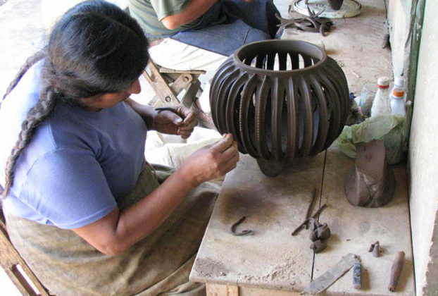 Cecilia painstakingly places tiny clay beads along the rib of a cactus-shaped pot.