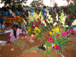 Indigenous women carry their food and flowers to the pueblo cemeteries in the traditional way — in baskets balanced on their heads.