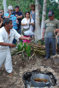 Copal incense is a part of traditional Maya religious ritual. The village shaman performs a ceremony as an underground oven, or pib is opened. Pork that has roasted there overnight will form part of the Day of the Dead celebration in this Mexico town. © Jane Ammeson, 2009