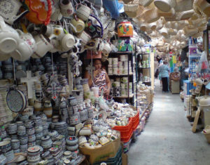 Handwoven wicker baskets hang from the ceiling in a Mexico market passageway. In the foreground are ceramics of all kinds in this view of the Tequisquiapan handicrafts market. © Daniel Wheeler, 2009