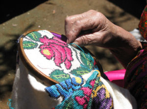 A wooden hoop holds the white cottton fabric as Hermelinda Reyes Ascencio awakens the bright colors hibernating in the guanengo. An embroidered blouse, the guanengo is traditional attire in Michoacan, Mexico. © Travis Whitehead, 2009