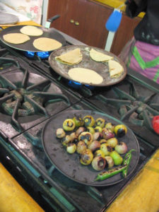 In Mexico, the comal is used for many purposes. Here, masa is cooked to become tortillas, tortillas are filled and folded to become quesadillas, while tomatillos and chile are charred on yet another griddle. © Alvin Starkman 2008