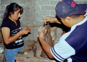 Francisco Barocio Jacobo puts an arm on a large Catrina while María works on a smaller piece in their Capula workshop.