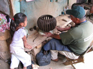 José María Alejos Madrigal's granddaughter watches while he works on a cactus pot.