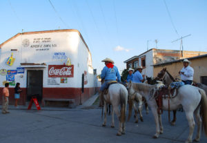 In the Querétaro town of Cadereyta de Montes, near Bernal, a men on horseback stop at a convenience store to stock up on bottles of water and then buy fresh corn on the cob from a street vendor. They are part of a group that meets once a week to ride between the towns. © Jane Ammeson 2009