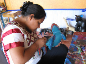 Jacobo Angeles' wife Maria carefully paints a carving by hand. Their colorful wood carvings are suprb examples of Mexican folk art. © Alvin Starkman 2008