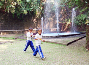 Children stroll past Arco Iris, a popular water formation that frequently captures a fleeting rainbow (hence the name) in its plumes.