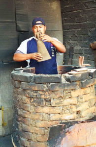 Francisco Barocio Jacobo carefully places a ceramic Catrina in a kiln outside the family workshop in Capula.
