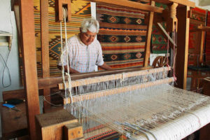 Porfirio Santiago adjusts the warp on his wide two-heddle handloom. The master weaver creates stunning Zapotec rugs in his Teotitlan del Valle workshop in Oaxaca. © William Ing, 2007