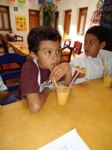 Smoothies are prepared and poured into plastic cups accompanied by straws and small decorative drink umbrellas. At Chef Pilar Cabrera's Casa de los Sabores Cooking School in Oaxaca, Mexico, children learn the basics of kitchen safety and hygiene, composting and recycling, and nutrition, all in a three-hour session. © Alvin Starkman, 2011