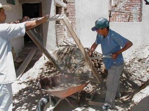 All concrete for this year-long project has been mixed on site, by hand. Here, two of the workers size the sand, separating the good sand from the trash and gravel. Next they will add cement and water, and prepare the mix. Proportions vary depending on the intended use.