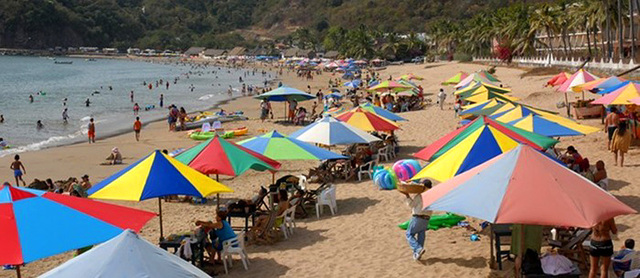 Colorful umbrellas shade beach chairs along the shore in Melaque, a small Mexico beach town. © Gerry Soroka, 2009